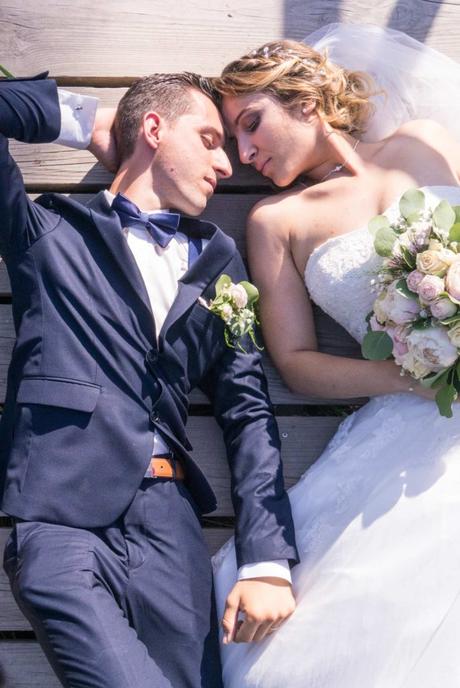 Les mariés allongés, tête contre tête, rêvent les yeux fermés.