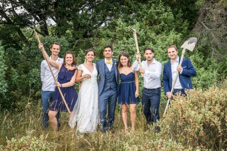 Mariage à Uzes. Les mariés posent avec leurs amis dans un champ. Ils brandissent des outils de travailleurs.