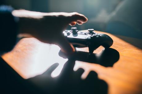 Une main tendue vers un contrôleur de jeu vidéo.