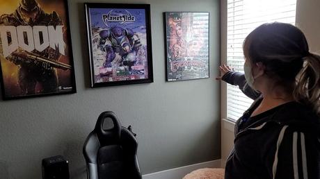 Fisa Castellanos montre des affiches pour Everquest II et Doom accrochées de chaque côté de son affiche Planetside.  (Spectrum News 1)