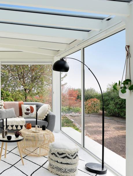 salon lumineux veranda baie vitrée accessoire rotin tapis berbère noir et blanc