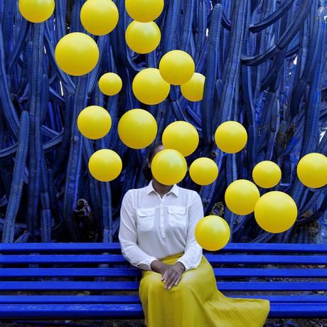 Des grappes de ballons brillants enveloppent la photographe Fares Micue dans ses autoportraits expressifs