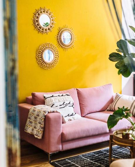 salon estival mur jaune canapé rose pastel coussin frange tapis noir et blanc