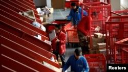 Les livreurs déplacent des colis d'une bande de tri automatisée vers des chariots dans un centre logistique intelligent de JD.com lors du festival du shopping Singles Day, à Pékin, en Chine, le 11 novembre 2020. REUTERS / Tingshu Wang