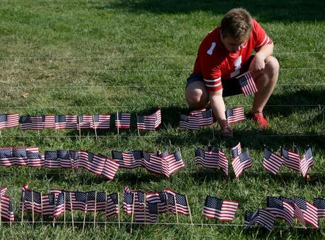L'ancien élève de l'État de l'Ohio, Peyton Sawyer, place un drapeau dans un affichage en l'honneur du 11 septembre 2001, à l'extérieur de la St. John Arena avant le match de football de la division I de la NCAA de samedi entre les Buckeyes de l'Ohio et les Ducks de l'Oregon le 11 septembre 2021. L'affichage faisait partie de la N'oubliez jamais le projet.