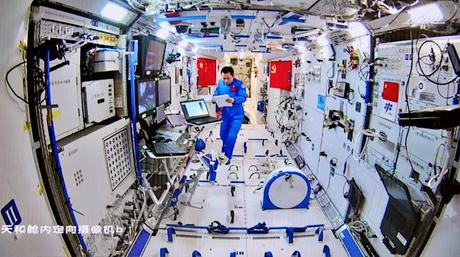 astronaute taïkonaut dans la station spatiale chinoise regardant des papiers portant une combinaison bleue