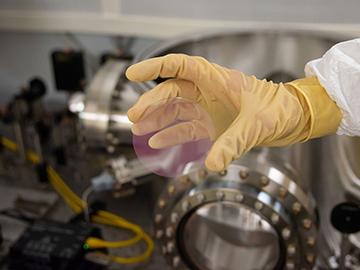 Optics & Photonics News – Les revêtements optiques à faible bruit pourraient augmenter la portée de LIGO photo d'une main tenant un échantillon de test