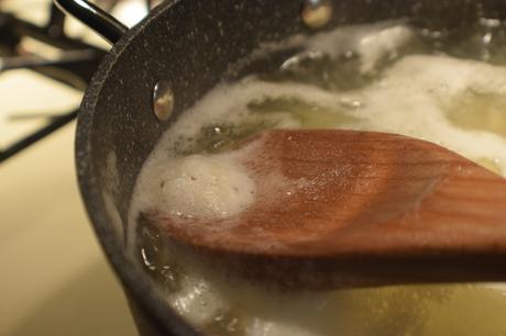 Ecumer l'amidon de l'eau bouillante avec une cuillère en bois.