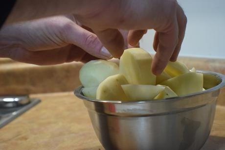 Des mains d'homme mettant des pommes de terre dans un bol en métal