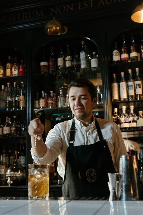 Un barman mélangeant une boisson dans un bar avec une cuillère.