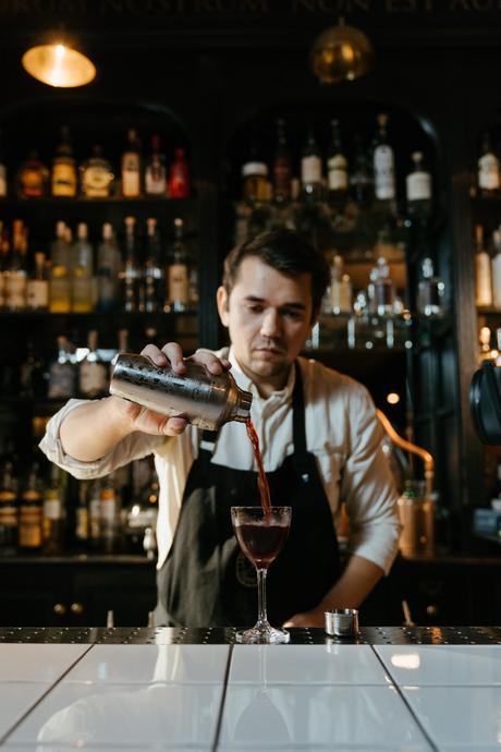 Un barman verse une boisson dans un shaker à martini dans un bar.