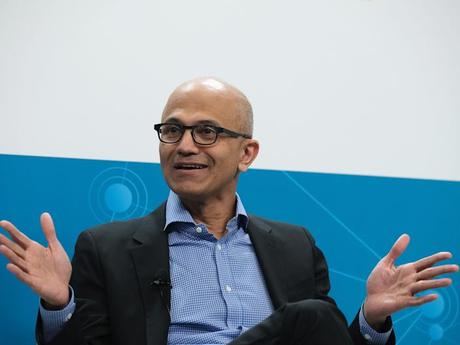 Le PDG de Microsoft, Satya Nadella, assis les mains ouvertes.