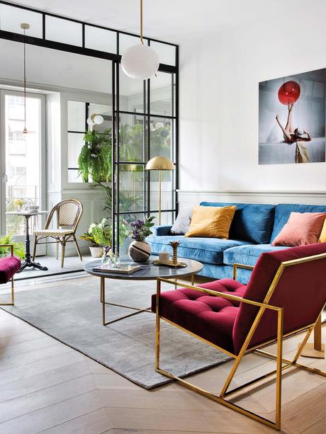 salon lumineux canapé bleu velours fauteuil rouge support table suspension en laiton