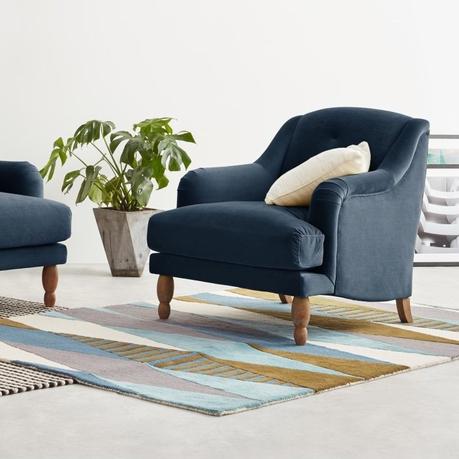 canapé bleu foncé pieds bois déco lounge tapis géométrique coloré