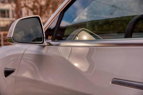 Photographie d'une voiture grise Photographie de côté d'une voiture grise avec un gros plan sur le rétroviseur qui reflète le siège conducteur