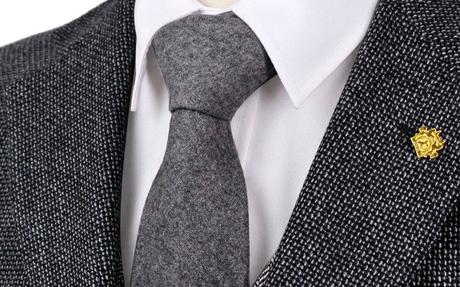Gros plan sur une cravate en laine grise unie nouée autour du cou Cravate en soie grise associée avec un costume texturé et une chemise blanche