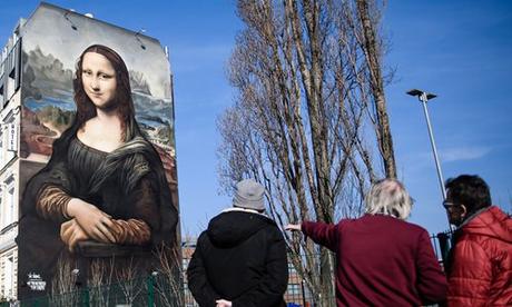 Des passants discutent devant une réplique géante de la peinture Mona Lisa de l'artiste italien de la Renaissance Léonard de Vinci peinte lundi sur la façade d'un hôtel à Berlin, en Allemagne.  Selon les médias, le portrait de plus de 16 mètres de haut et 11 mètres de large, situé en face de la East Side Gallery, a été réalisé par le collectif d'artistes berlinois Die Dixons.  Photo : IC