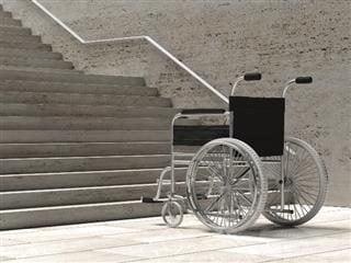 Fauteuil roulant vide devant des escaliers en béton.