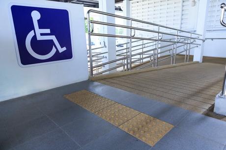 Un grand panneau pour fauteuils roulants est visible à gauche d'une rampe pour fauteuils roulants.