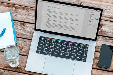 Commencez votre voyage de programmation avec HTML et CSS de base ordinateur portable sur une table à côté d'un verre d'eau, d'un ordinateur portable et d'un téléphone