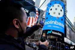 Un employé de Coinbase célèbre l'offre d'actions de la société d'échange de crypto-monnaie en 2021. Un peu plus d'un an plus tard, l'entreprise réduit ses effectifs car elle s'attend à un ralentissement économique.  (AP Photo/Richard Drew)