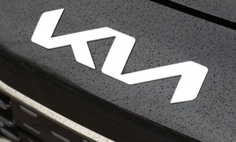 Nouveau logo angulaire de KIA Motors sur le capot noir de la Kia Rio rouge avec des gouttes d'eau.