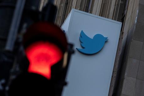 Le logo Twitter sur un bâtiment photographié derrière un feu rouge. 