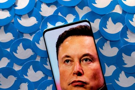 Une image d'Elon Musk est vue sur un smartphone placé sur un grand nombre de logos Twitter imprimés