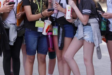 un groupe de jeunes filles debout et utilisant leurs téléphones portables, vous ne pouvez voir que leurs jambes