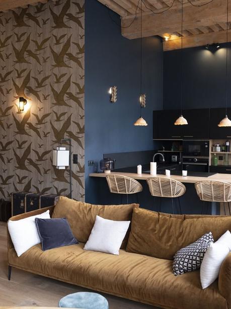 salon cuisine ouverte canapé velours jaune taupe chaise haute rotin mur bleu