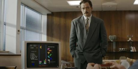 Henk Rogers de Taron Egerton regarde quelqu'un jouer à Tetris.