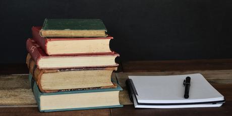 Pile de livres et bloc-notes sur table en bois